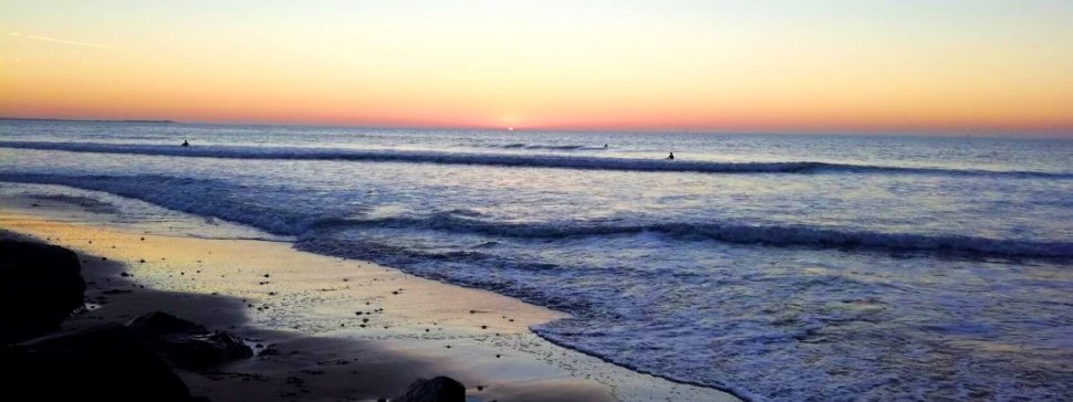 trois baigneurs se baignent dans les vagues sur la plage du peu des hommes au coucher du soleil